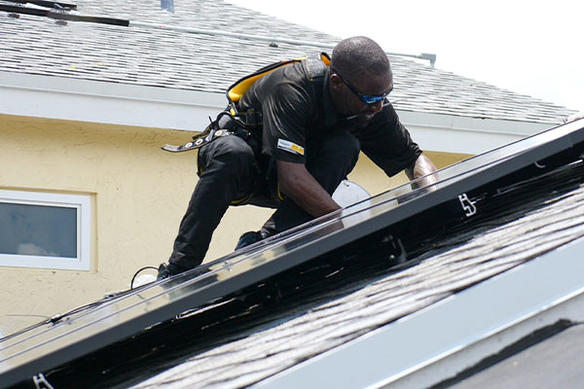 technician installing a solar panel on a roof