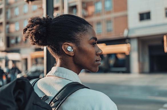Woman wearing Technics earbuds while on the street