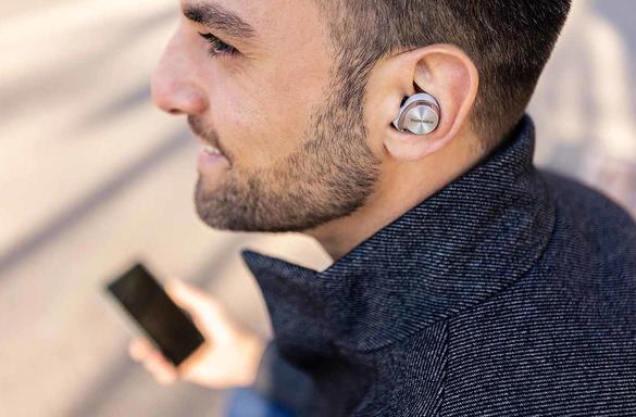 Man wearing Technics earbuds while using mobile phone