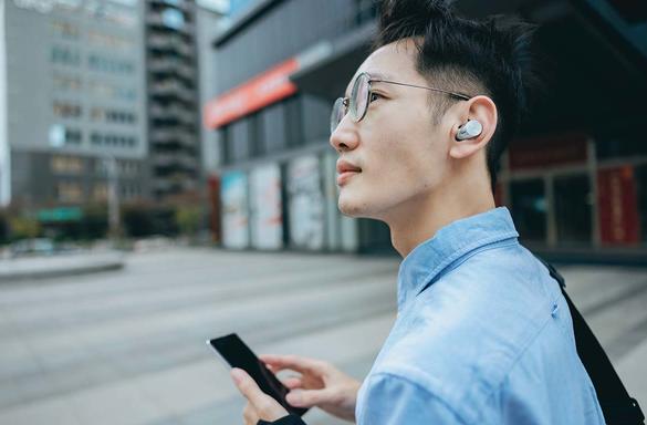 Man wearing Technics earbuds while walking on street