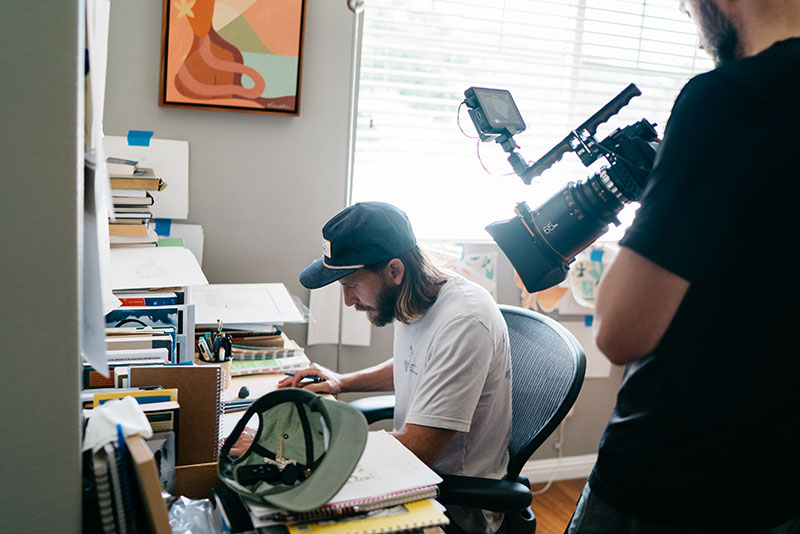 Filmmaker Andrew Rizer shoots artist Nick Kuchar over the shoulder creating at his desk