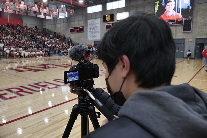 Student looking at the LCD screen on a LUMIX camera while shooting in a gymnasium