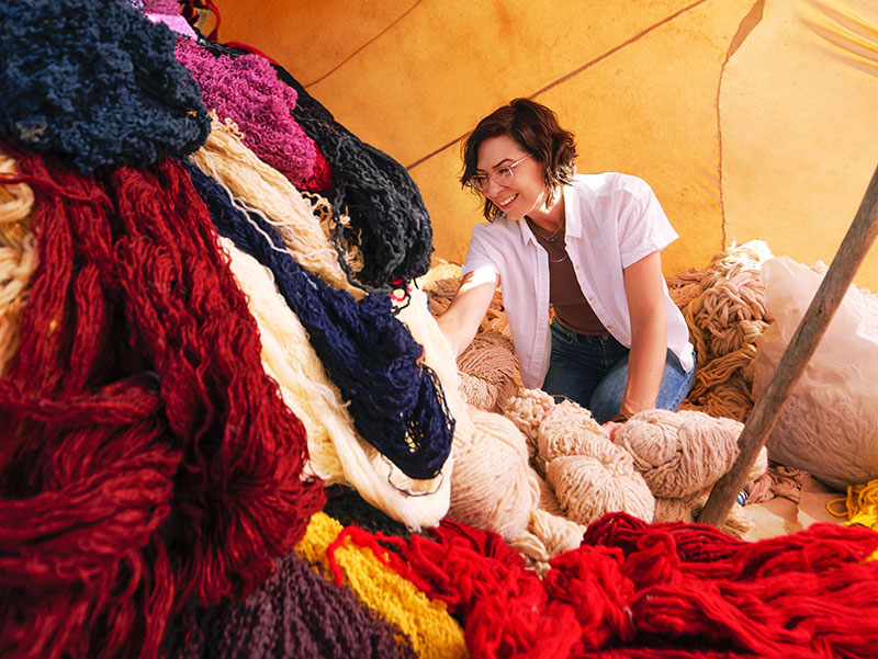 Lesli Robertson inspecting a number of hand woven rugs