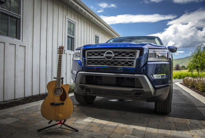 Exterior shot of a Nissan Frontier next to a Fender acoustic guitar