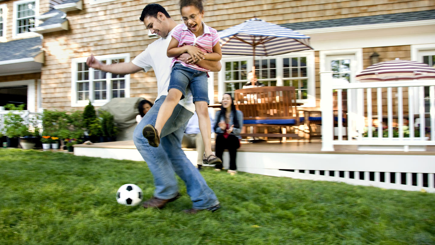 Father playing soccer with daughter in backyard