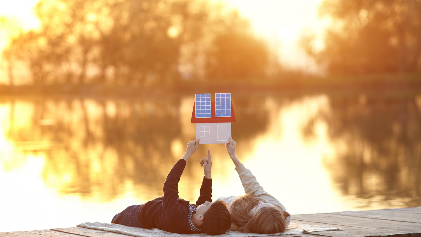 Happy couple of children dreaming of a house with solar panels