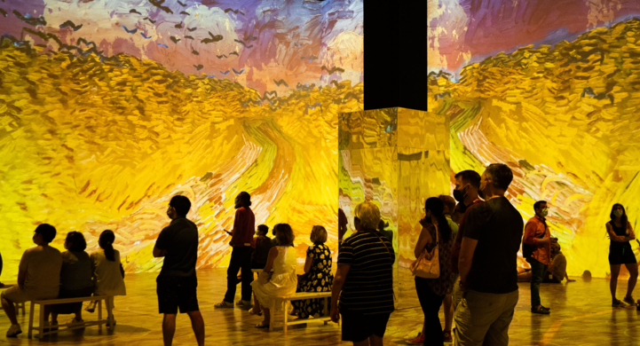 Socially distanced groups stand amidst an immersive Van Gogh experience