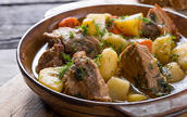 beef pot roast with sliced carrots and potato chunks in brown earthenware bowl