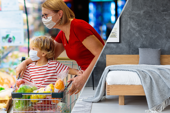 An image of a mother and son grocery shopping. They are wearing masks and the son rides in the shopping cart.