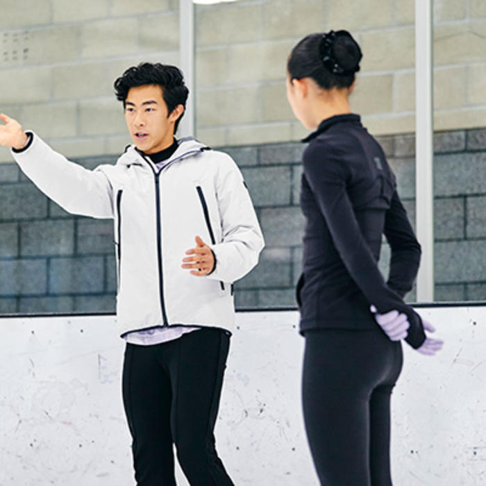 Nathan Chen discussing his routine with a coach on the ice