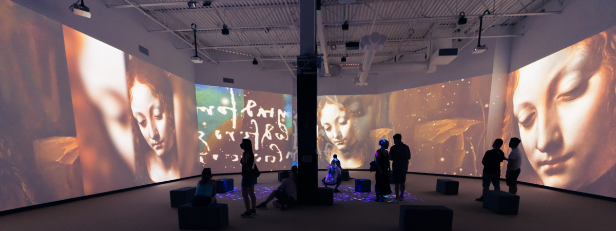 a group of on-lookers stand amidst moving projections highlighting the works of Leonardo Da Vinci