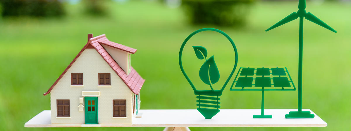 Future clean / renewable or alternative energy for modern living concept : House model, light bulb with green leaf, solar panel, wind mill on wood balance scale, depicts the awareness of environment.
