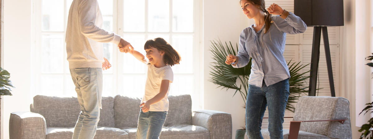 Family dancing in living room spending time on weekend together