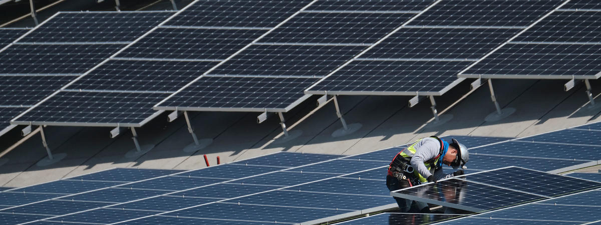In this Aug. 8, 2019 photo a worker helps to install solar panels onto a roof at the Van Nuys Airport in the Van Nuys section of Los Angeles.