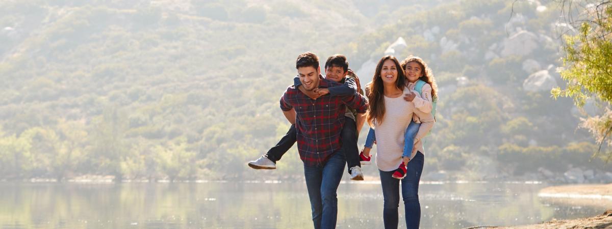 Parents piggybacking their young children by a mountain lake