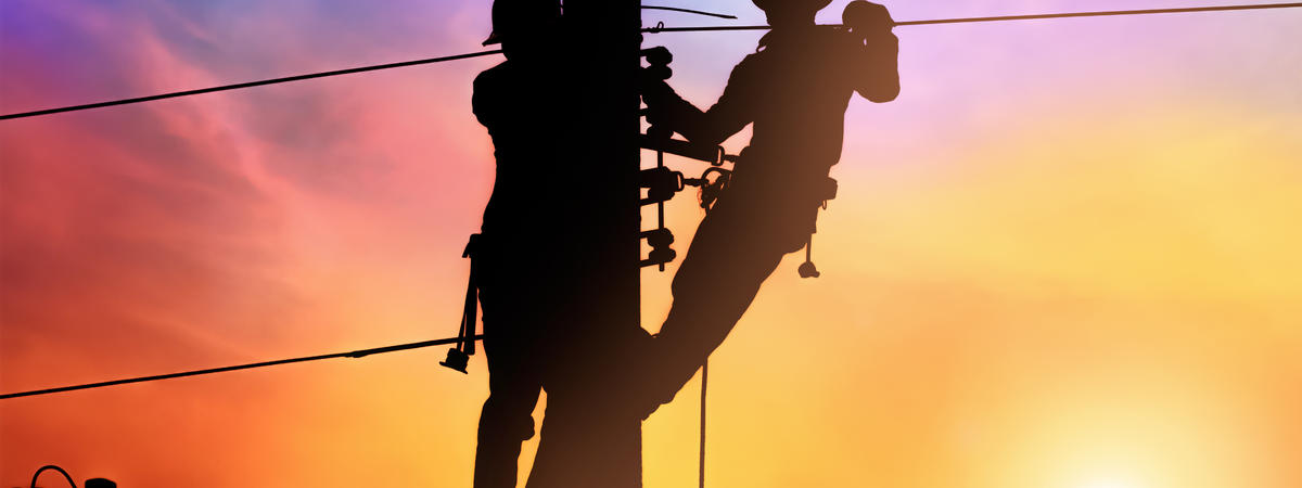 Silhouette two electrical engineer on electricity pole, work on electric post power pole and repair power outage.