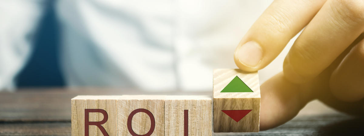 Wooden blocks with the word ROI and green arrow up. High level of business profitability. Return on investment, invested capital, rate. Success. Growth. Analytics. Report