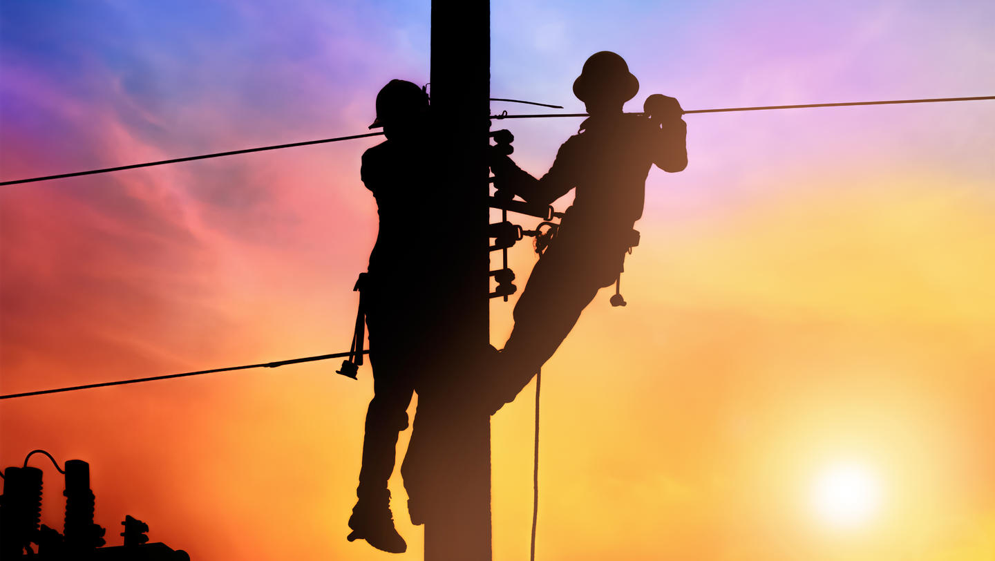 Silhouette two electrical engineer on electricity pole, work on electric post power pole and repair power outage.